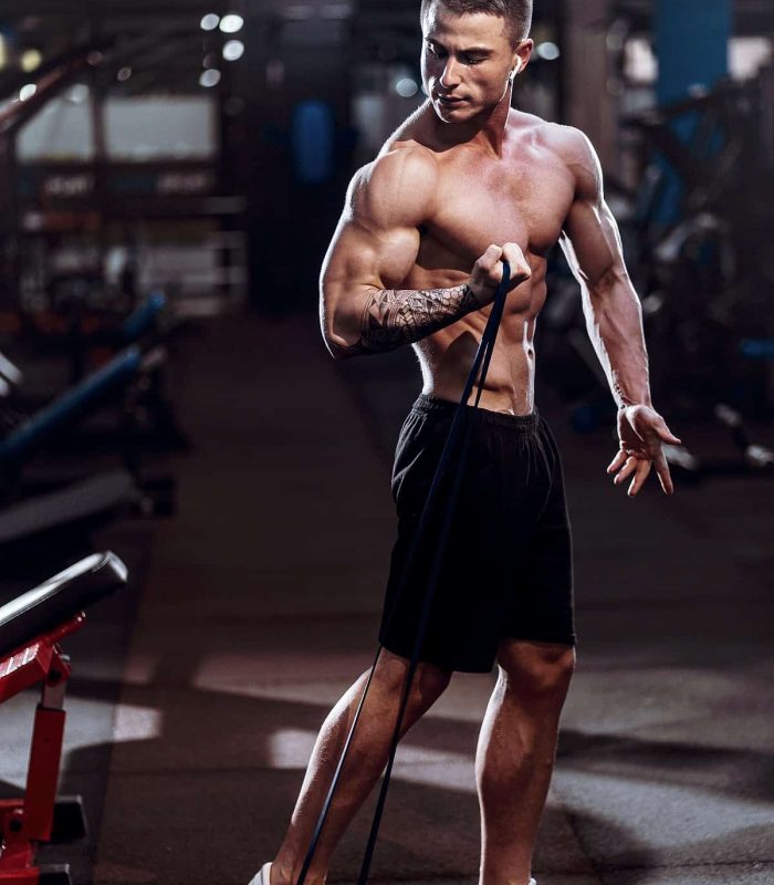 Hard working well built sportsman exercising with a resistance band in gym